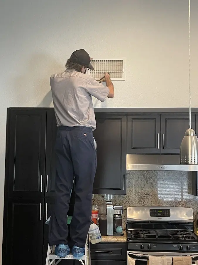 Technician inspecting an air vent during HVAC service in Lake Mills